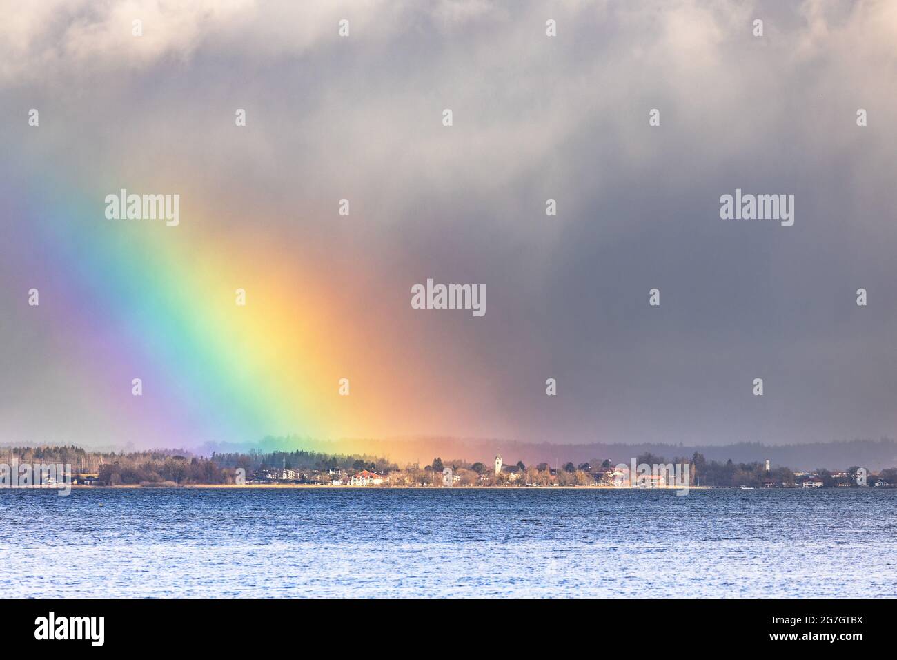 El arcoiris luminoso ilumina la pequeña ciudad en la orilla del mar, frente thundery en el fondo, Alemania, Baviera, Lago Chiemsee, Seebuck Foto de stock