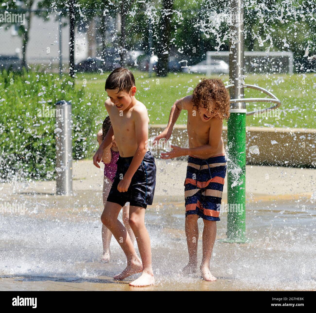 Tres niños (de 7 y 9 años) jugando en juegos acuáticos y fuentes en la ciudad de Quebec, Canadá Foto de stock