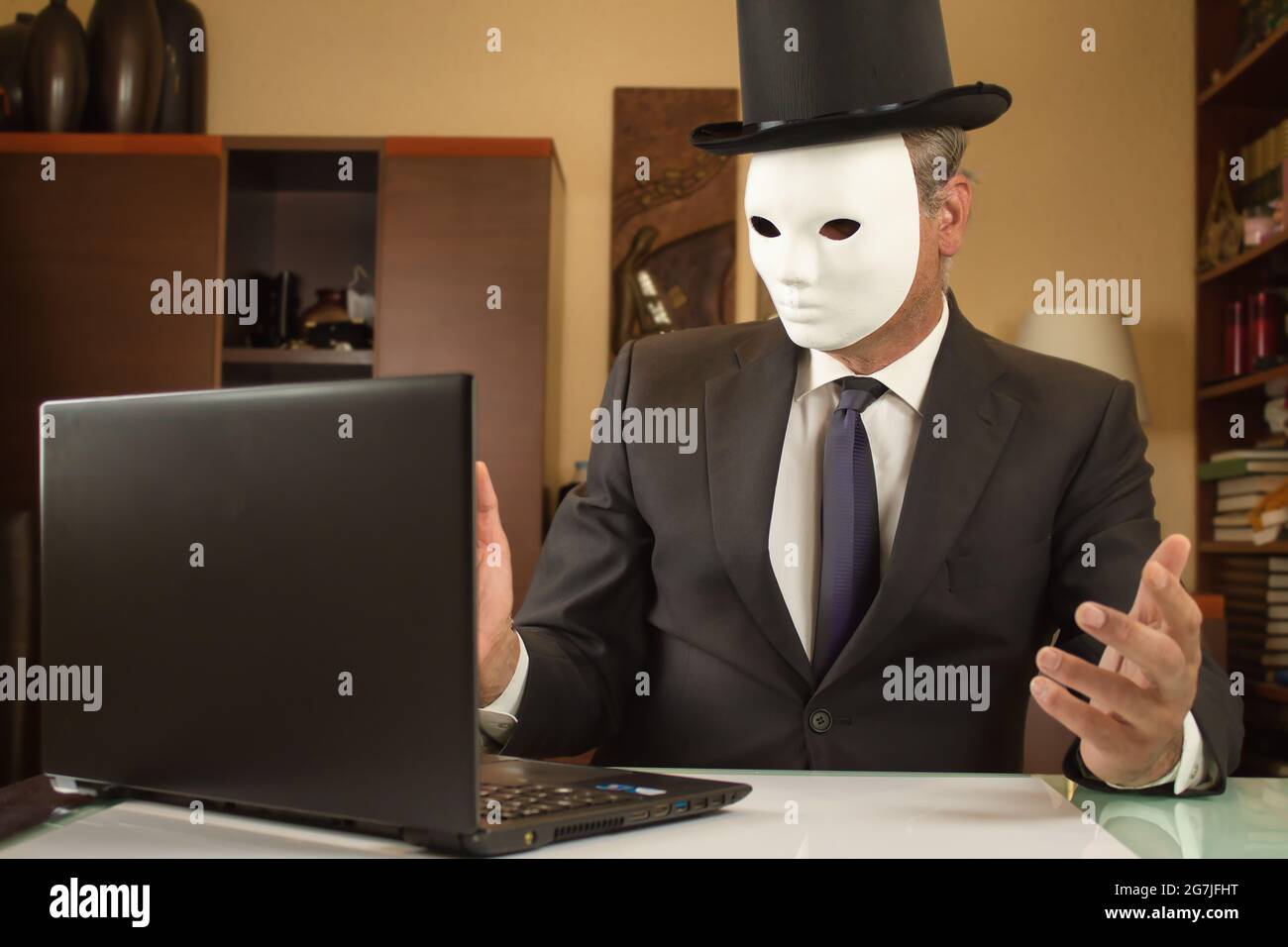 hombre de negocios camuflado con una máscara y un sombrero teletrabajo desde casa debido a restricciones de covid Foto de stock