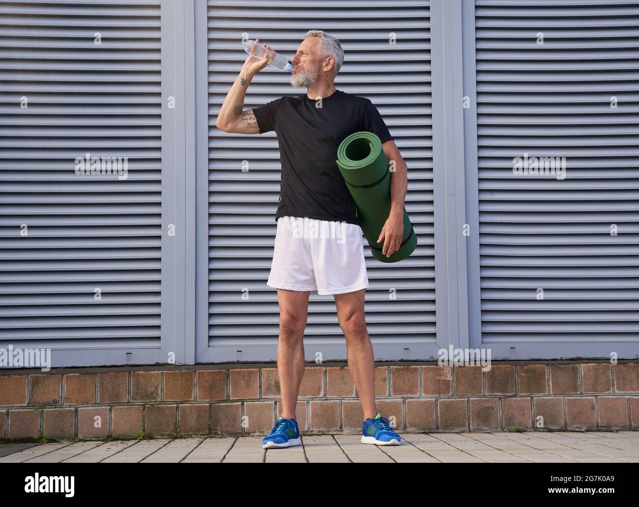 El de mediana edad deportivo bebiendo agua, sosteniendo la de ejercicio, listo para hacer deporte al aire libre Fotografía de stock - Alamy