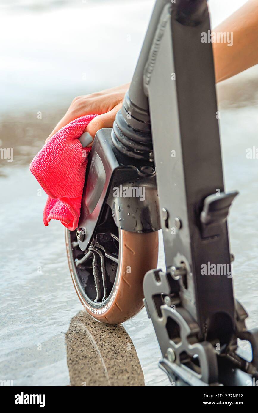 Limpieza o lavado del scooter. Cuidado del scooter eléctrico. Una mujer  limpia una scooter con un trapo después de lavarla con agua. Lugar para el  texto Fotografía de stock - Alamy