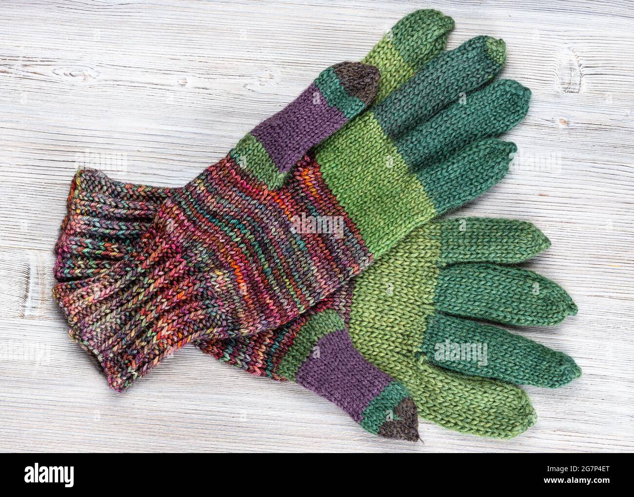 vista superior de un par de guantes de lana tejidos a mano sobre una mesa de madera gris Foto de stock