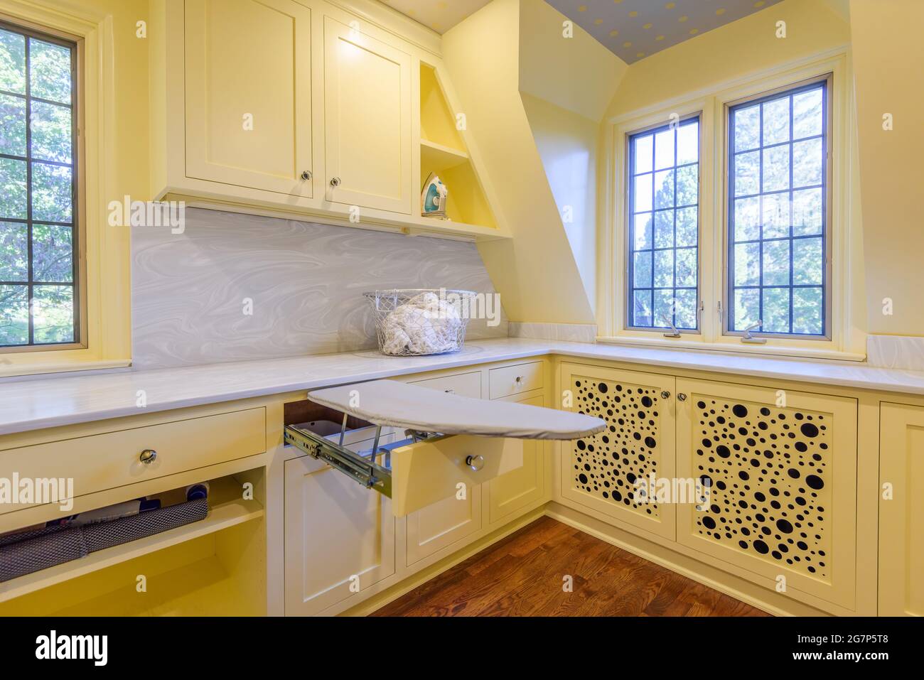 Lavandería en una casa tudor inglesa, pintada de amarillo con burbujas pintadas en los armarios. Foto de stock