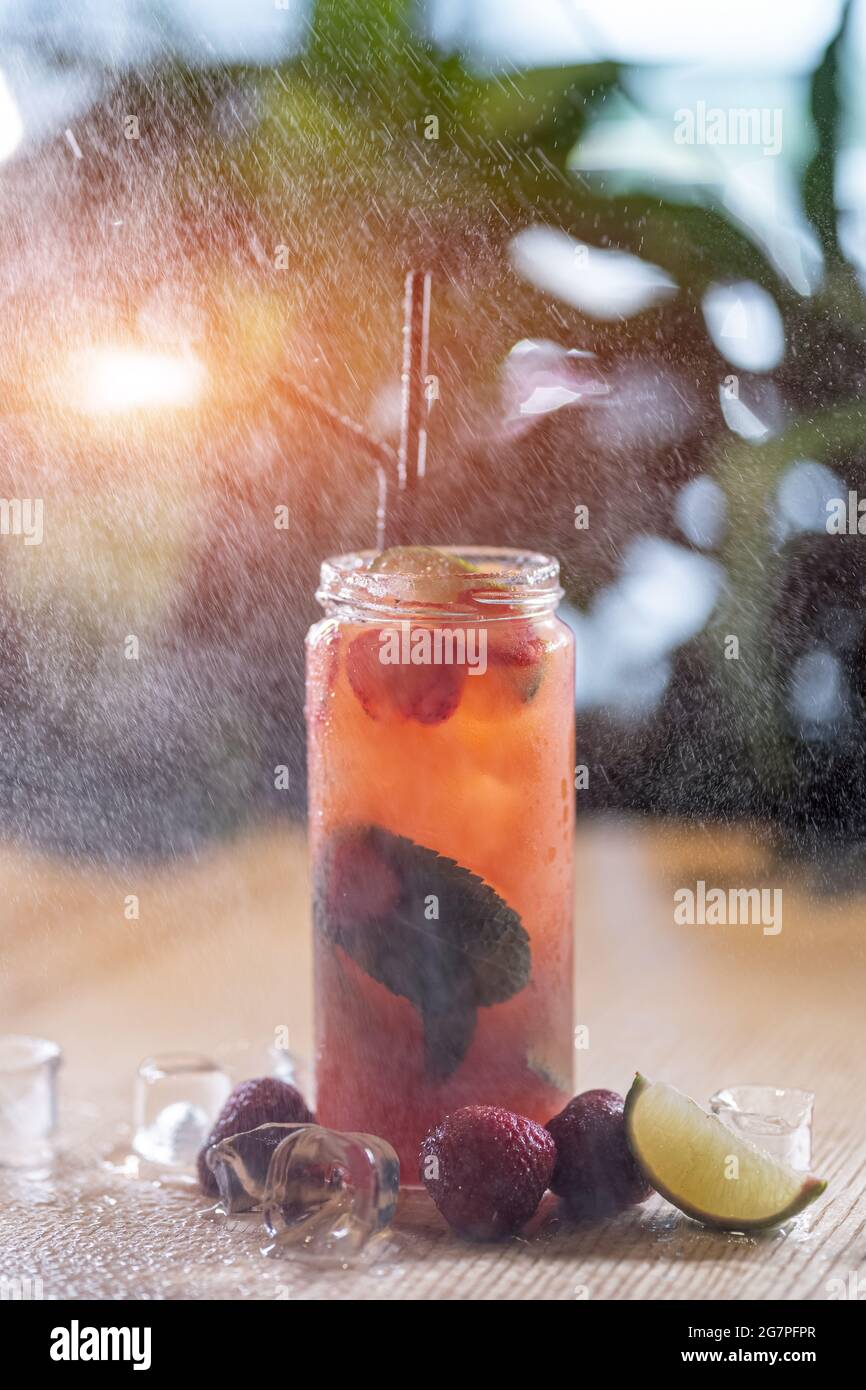 limonada de fresa beba con menta y hielo en botella de vidrio bajo aerosol de agua Foto de stock