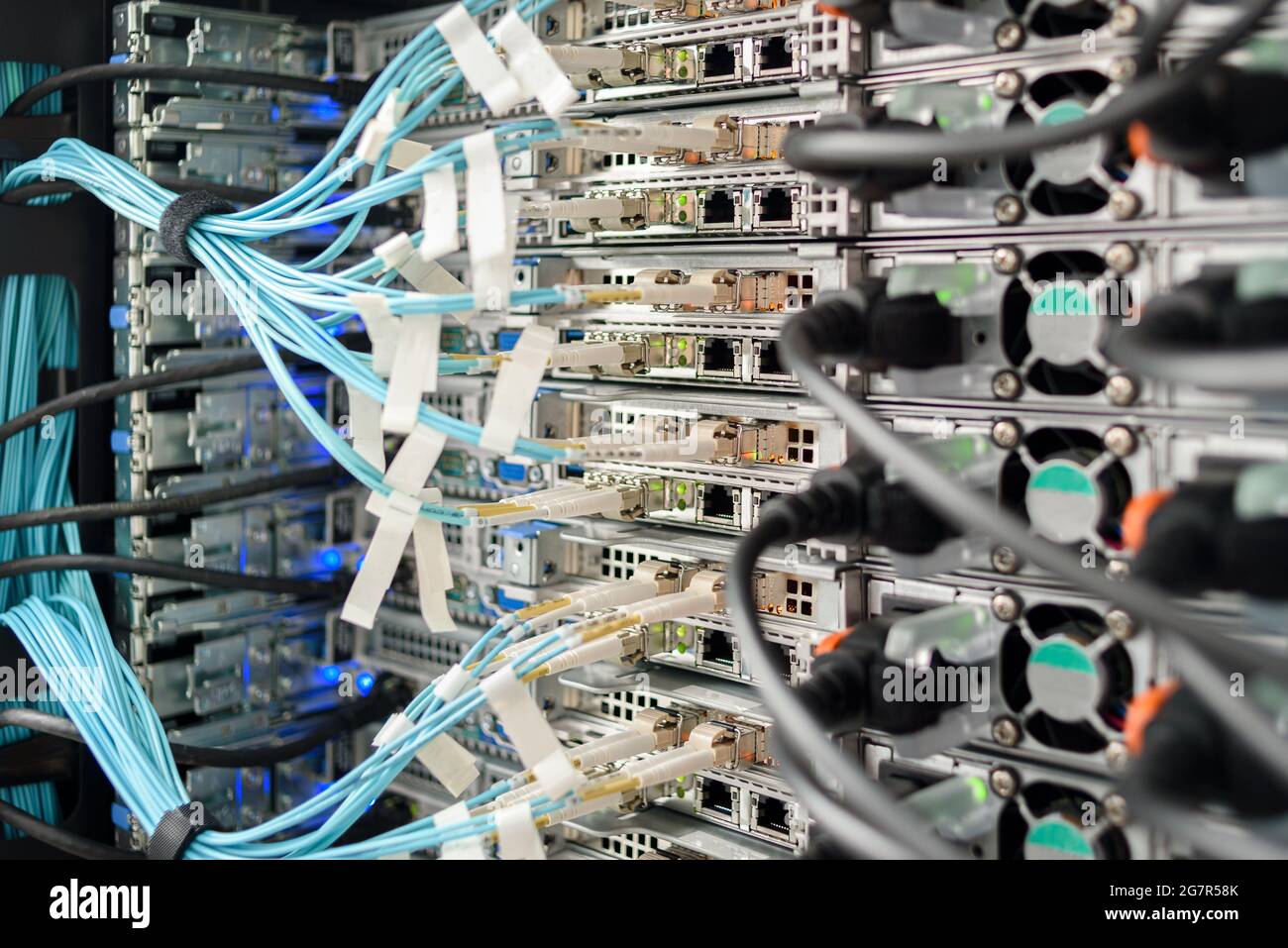 Servidores, switches o routers en funcionamiento en el centro de datos con una gran cantidad de lámparas y cables LED Foto de stock