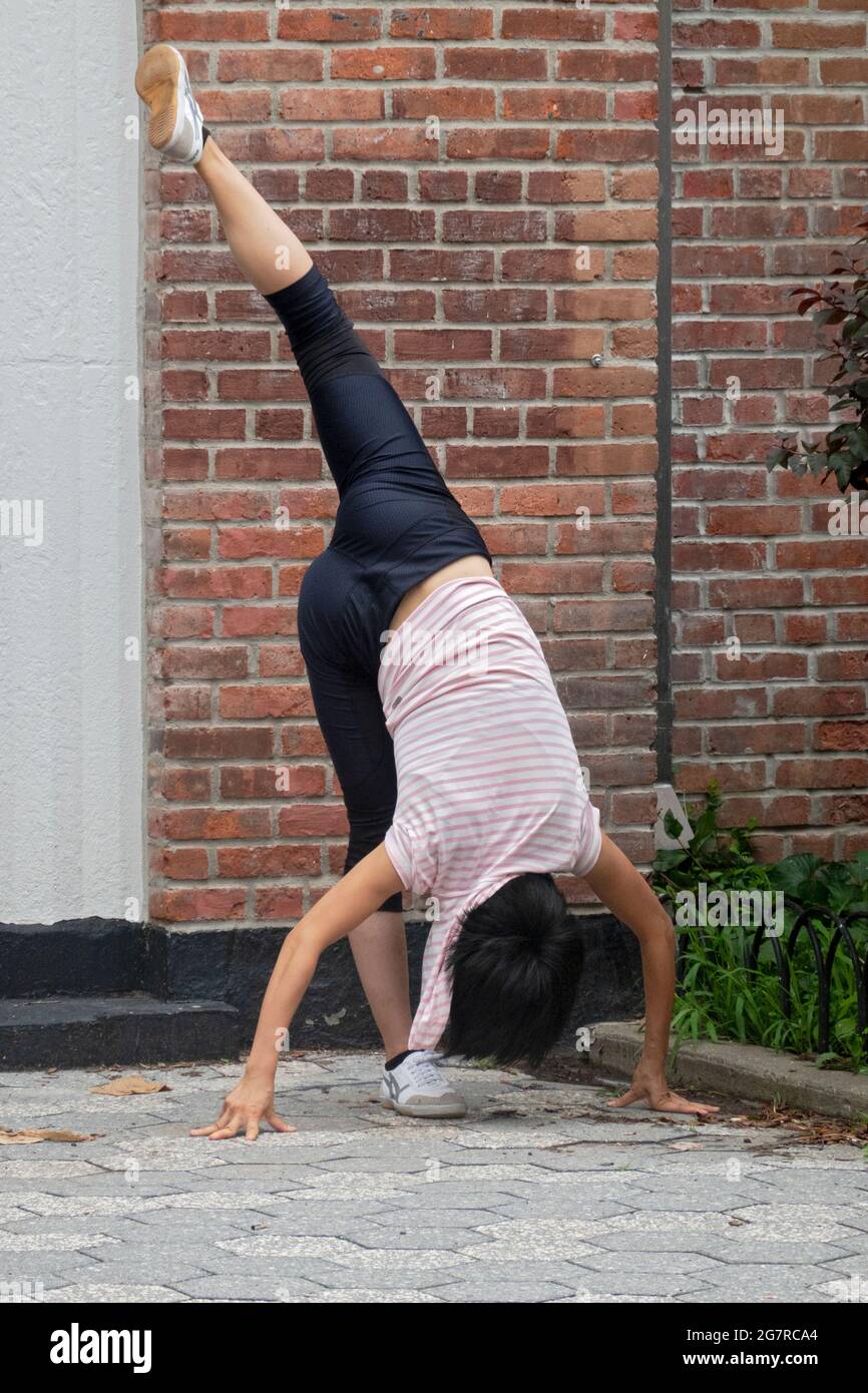 Una joven ágil flexible hace rigurosos ejercicios de estiramiento en un parque en la ciudad de Nueva York. Foto de stock