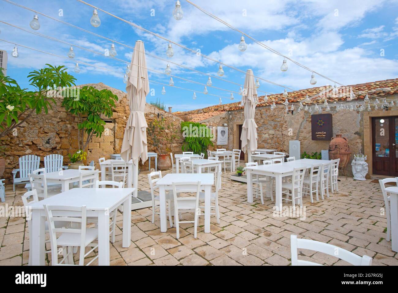 Mesas y sillas colouful en la Piazza Regina Margherita en la aldea de pescadores de Marzamemi, Sicilia Foto de stock