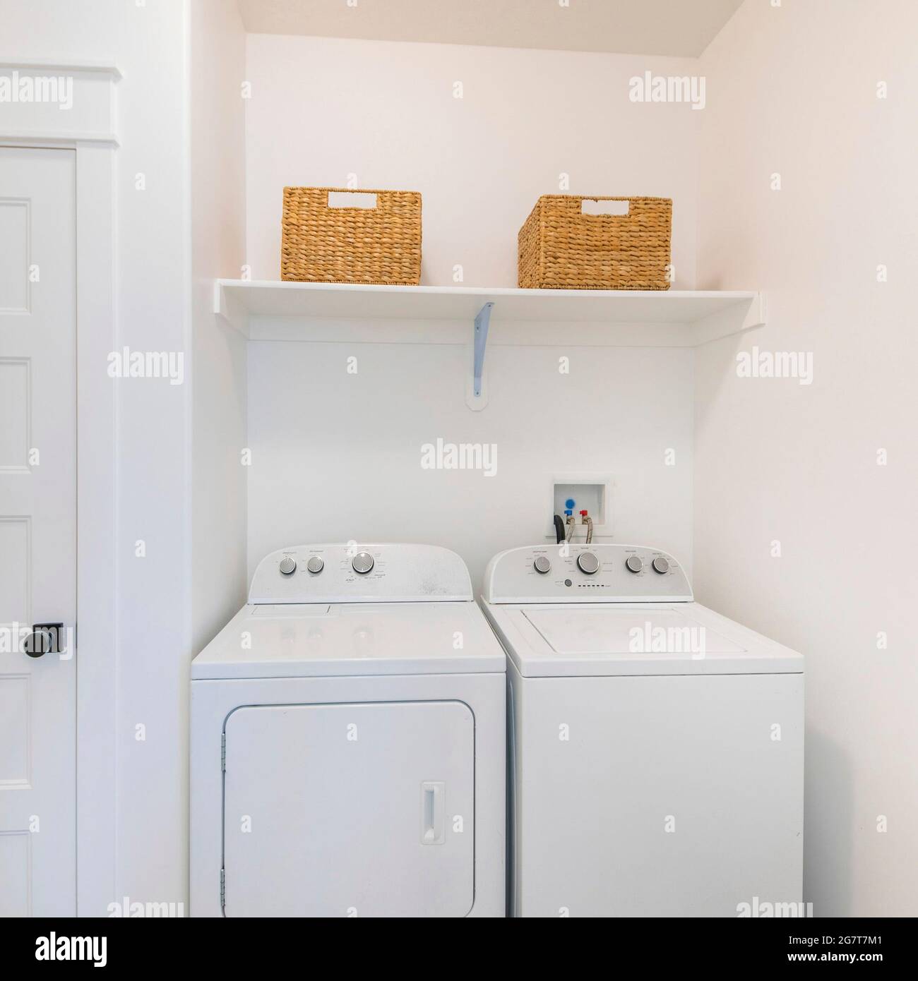 Marco cuadrado pequeño lavadero blanco interior con lavadora y secadora al  lado de una puerta estrecha blanca Fotografía de stock - Alamy