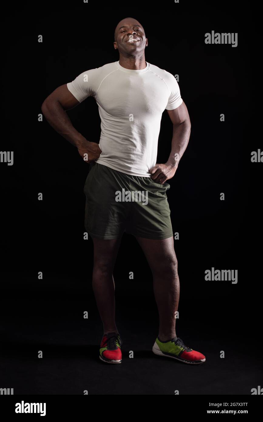 Hombre afroamericano de pie mirando la cámara con puños en la cintura Foto de stock