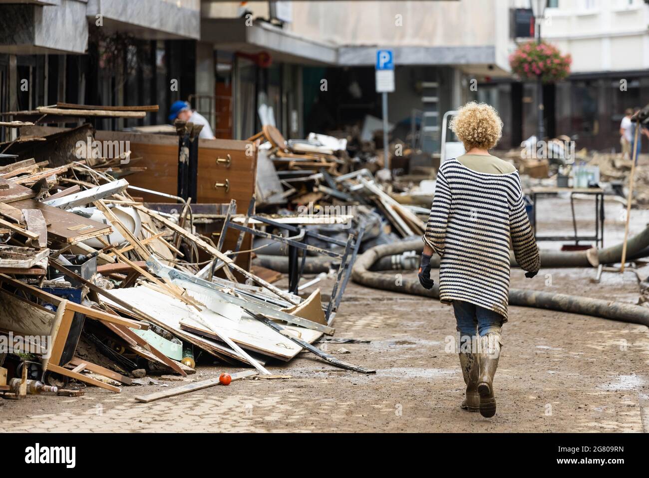 Bad Neuenahr, Alemania. 16th de julio de 2021. Una mujer sucia de barro camina por un montón de escombros. Objetos de una casa. Las lluvias masivas han causado inundaciones en Bad Neuenahr, Renania-Palatinado, así como en todo el distrito de Ahrweiler. Crédito: Philipp von Ditfurth/dpa/Alamy Live News Foto de stock