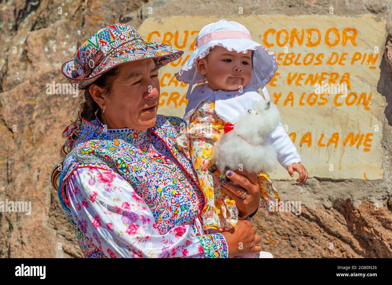 Mujer indígena Collagua con nieto posando junto a la Cruz del Cóndor, Cañón del Colca, Arequipa, Perú. Foto de stock