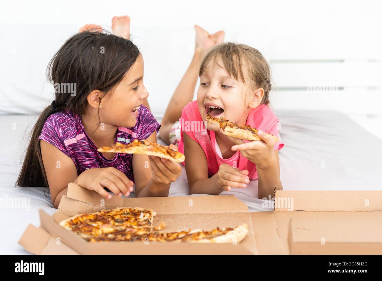 Dos muchachas jóvenes bonitas comiendo una porción de pizza Fotografía de  stock - Alamy