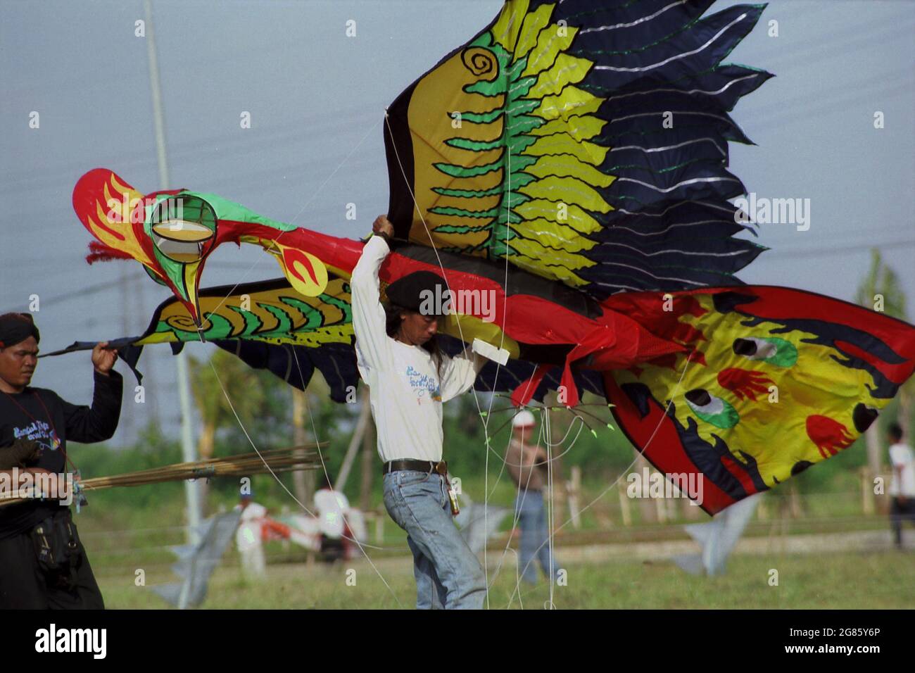 Un participante que transportaba una cometa gigante que fue diseñada para representar a un Garuda durante el Festival Internacional de Kite de Yakarta 2004 que tuvo lugar el 9-11 de julio en Carnival Beach en Ancol Dreamland, North Jakarta, Yakarta, Indonesia. Foto de stock