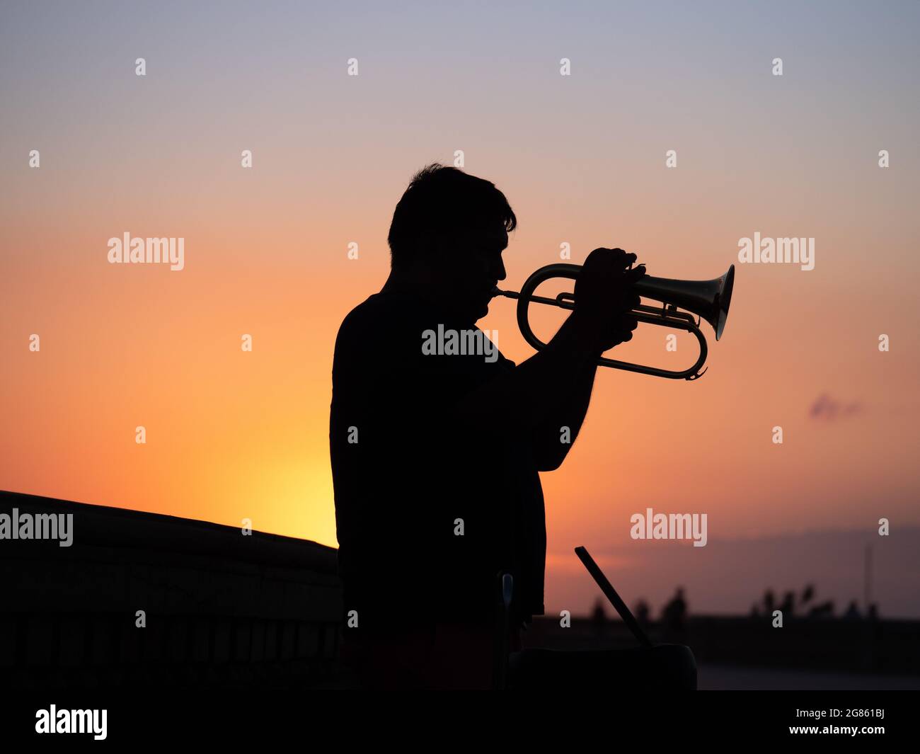 Silueta de un trompetista solitario tocando su trompeta en Sunset en un