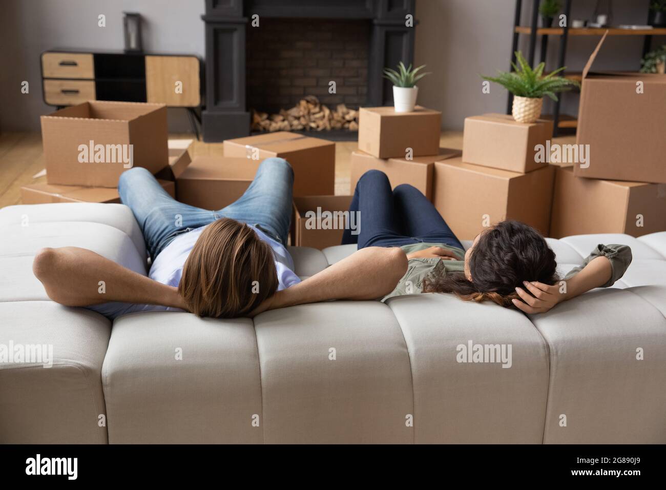 Una pareja se relaja en el sofá de la nueva casa en el día de mudanza Foto de stock