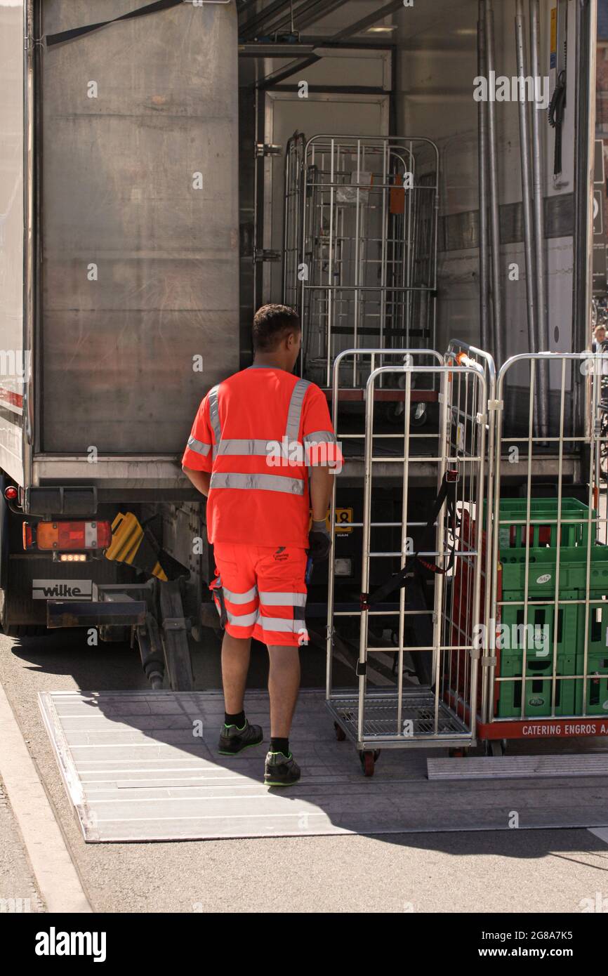 Hombre de origen en ropa de trabajo reflectante cargando productos lácteos en jaulas de metal de refrigerada. Copenhague, - 26 de junio de 2021 Fotografía de stock - Alamy