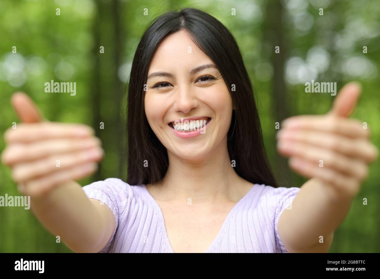 Vista frontal retrato de una feliz mujer asiática que invita a venir aquí invitándole en un parque Foto de stock