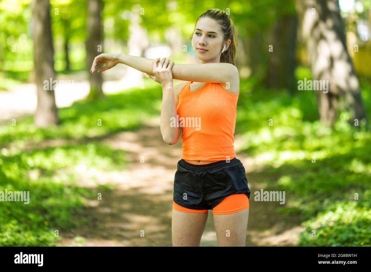 Mujer sprinter en ropa deportiva haciendo ejercicios de calentamiento antes  de correr en pista de estadio con revestimiento rojo al aire libre  Fotografía de stock - Alamy