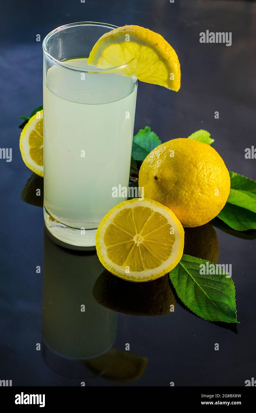 zumo de limón fresco y limón sobre un fondo oscuro Foto de stock