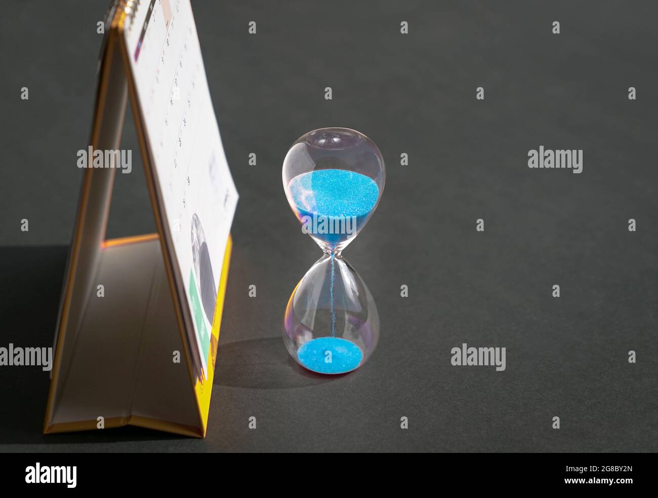 Reloj de arena junto al calendario con espacio de copia. Concepto de citas o horarios de reuniones. Foto de stock