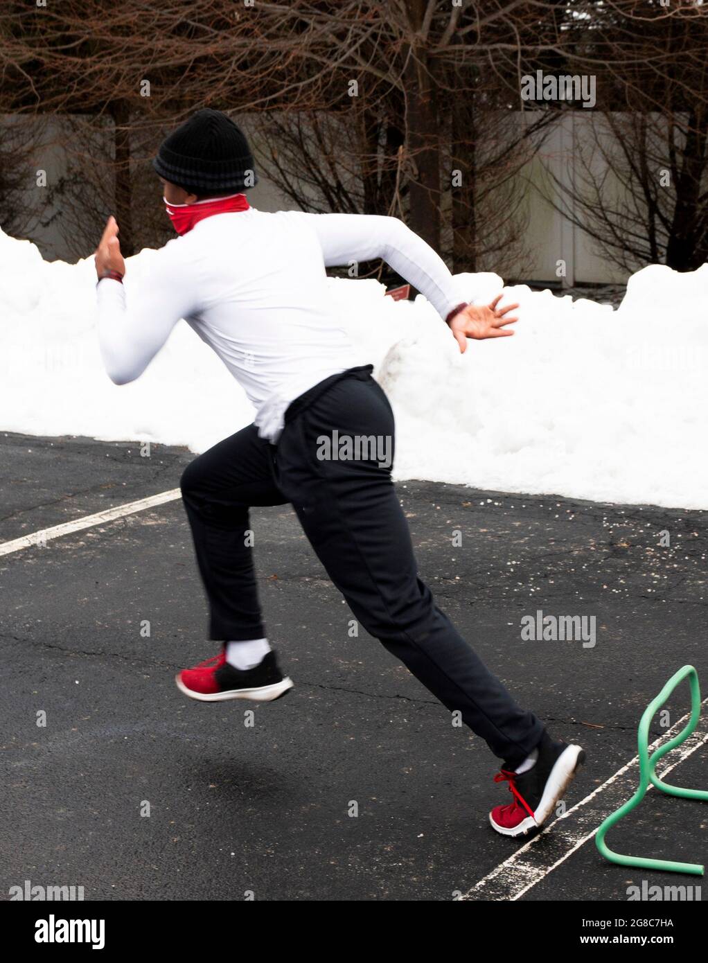 Fast High School pista y campo sprinter corredor corriendo sobre pequeños  obstáculos en un aparcamiento con nieve en el lado que lleva una máscara de  la cara fuelle Fotografía de stock -