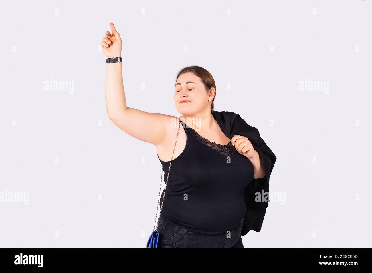 Mujer en camisa negra , jeans y bolso azul en una cadena con los ojos  cerrados es feliz con ella se levantó una mano Fotografía de stock - Alamy