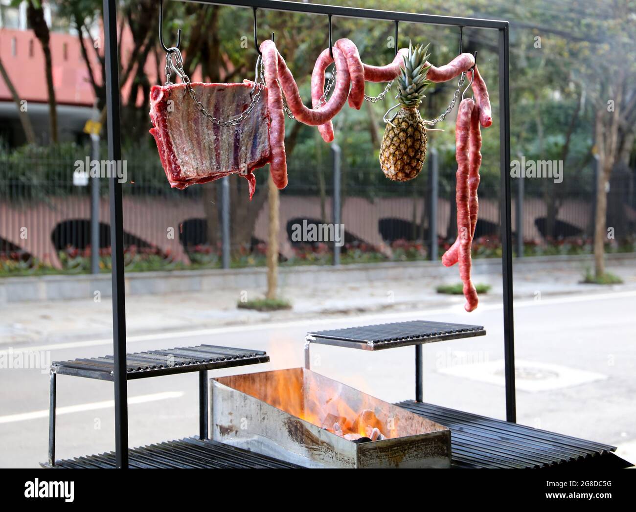 Parrilla de barbacoa argentina en la acera de una calle en Brasil. Con  fuego y salchichas colgantes Fotografía de stock - Alamy