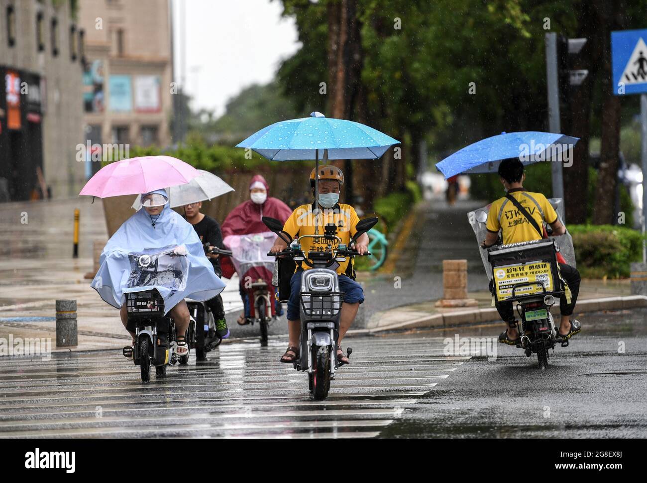 (210720) -- SHENZHEN, 20 de julio de 2021 (Xinhua) -- los residentes viajan en bicicletas eléctricas bajo la lluvia en Shenzhen, provincia Guangdong del sur de China, 19 de julio de 2021. Según las autoridades meteorológicas provinciales, se prevé que el tifón Cempaka, el séptimo de este año, se derrumbe el martes en la costa de la provincia china de Guangdong, en el sur de China. Cempaka, fortaleciéndose en un tifón el lunes por la mañana, se acercará lentamente a la región costera entre el estuario del río Pearl y el oeste de Guangdong, con su intensidad aumentando gradualmente, y hará tierra entre las ciudades de Zhuhai y Maoming entre el martes Foto de stock