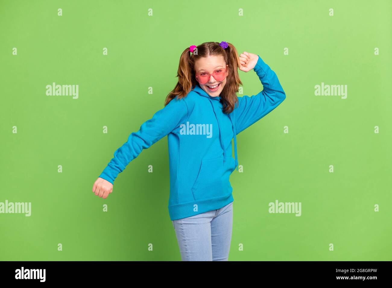 Foto de alegre joven chica funky buen estado de ánimo baile desgaste reloj  de sol corazón divertido aislado en el fondo de color verde Fotografía de  stock - Alamy