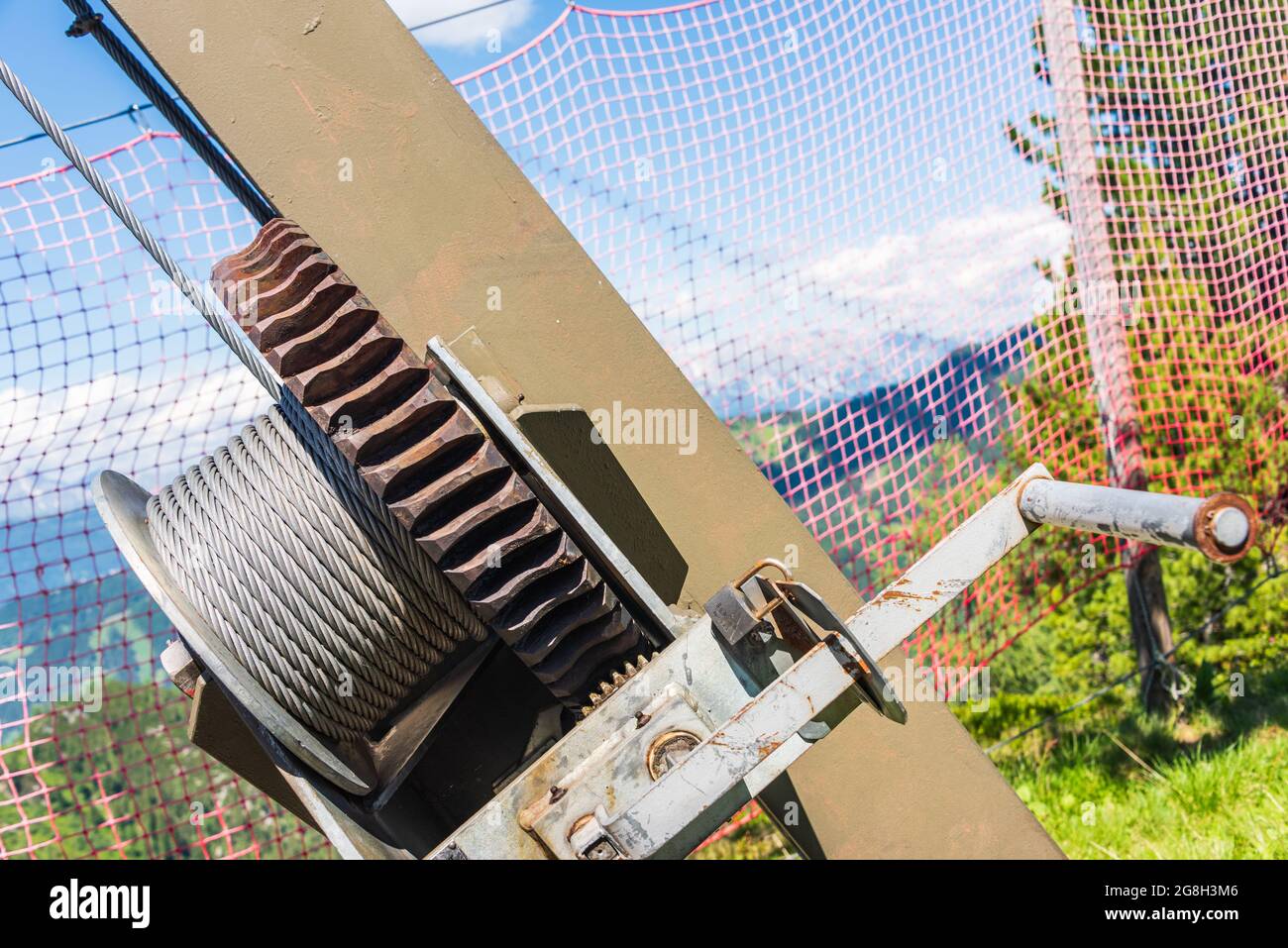 Engranaje y cuerda de acero y manivela. Fragmento de tensión de una grúa o estructura de acero. La cuerda de acero tiene un buen acabado, mientras que la rueda dentada es claramente r Foto de stock