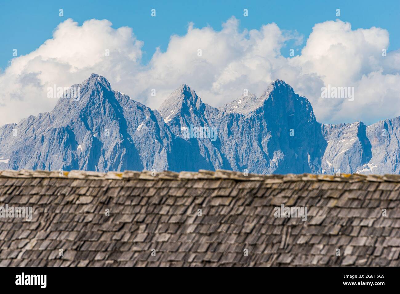 Blanqued weathered y se desvaneció del sol, lluvia y tejas de madera de la nieve que son el techo de una casa alpina contra el fondo de la alta montaña alpina Foto de stock