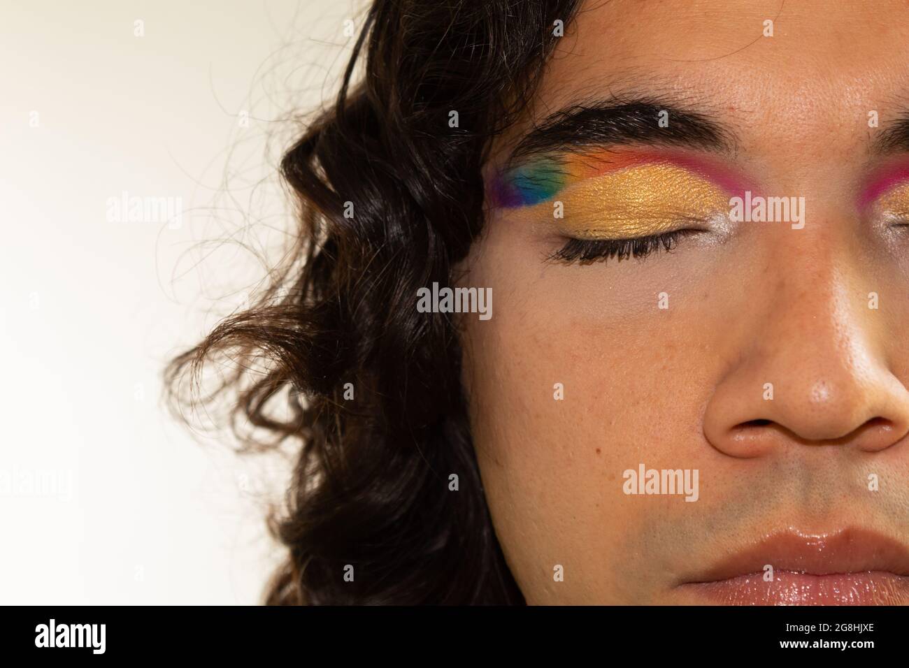 primer plano de la cara de un hombre gay hispano con maquillaje arcoiris  sobre un fondo blanco Fotografía de stock - Alamy