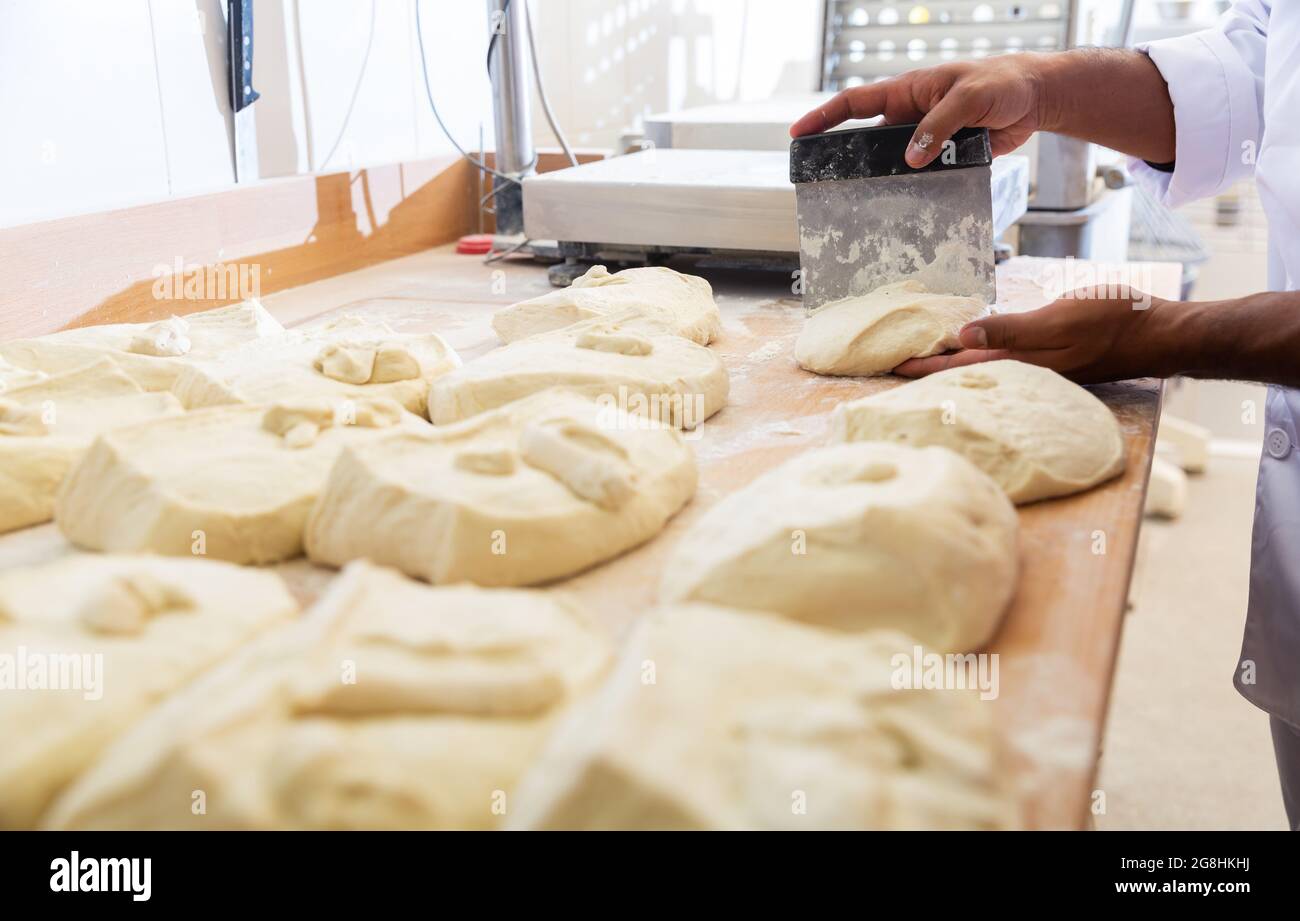 Manos de panadero porcionar la masa cruda con rasqueta Fotografía de stock  - Alamy