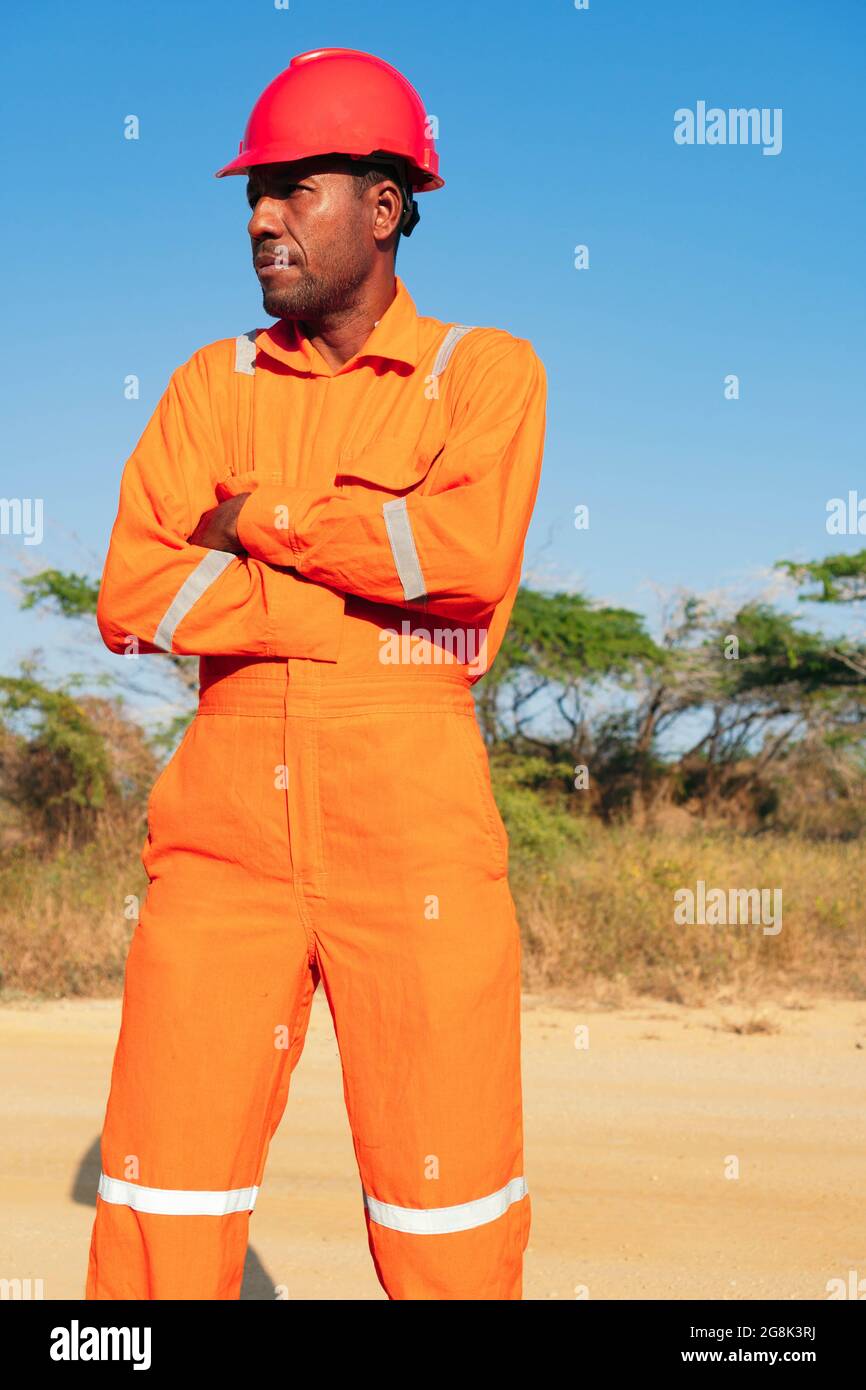 Concepto de ingeniero o técnico. Negro Macho mecánico en uniforme naranja  con los brazos cruzados Fotografía de stock - Alamy