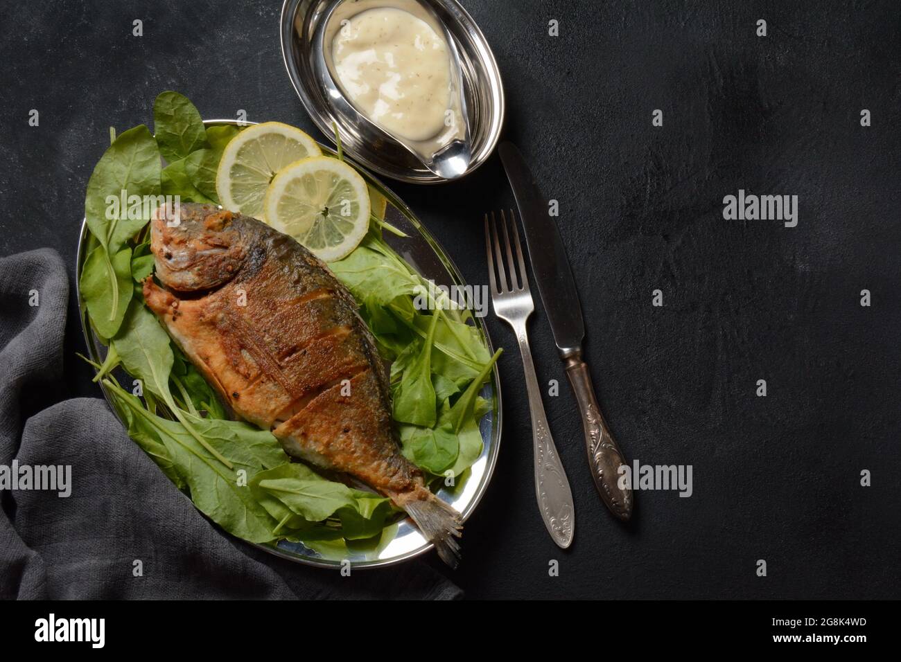 Pescado frito dorado con hierbas frescas y limón en bandeja de plata  Fotografía de stock - Alamy