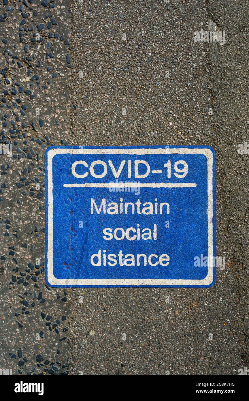 Azul COVID-19 signo de distanciamiento social pintado en pavimento o carretera. Foto de stock