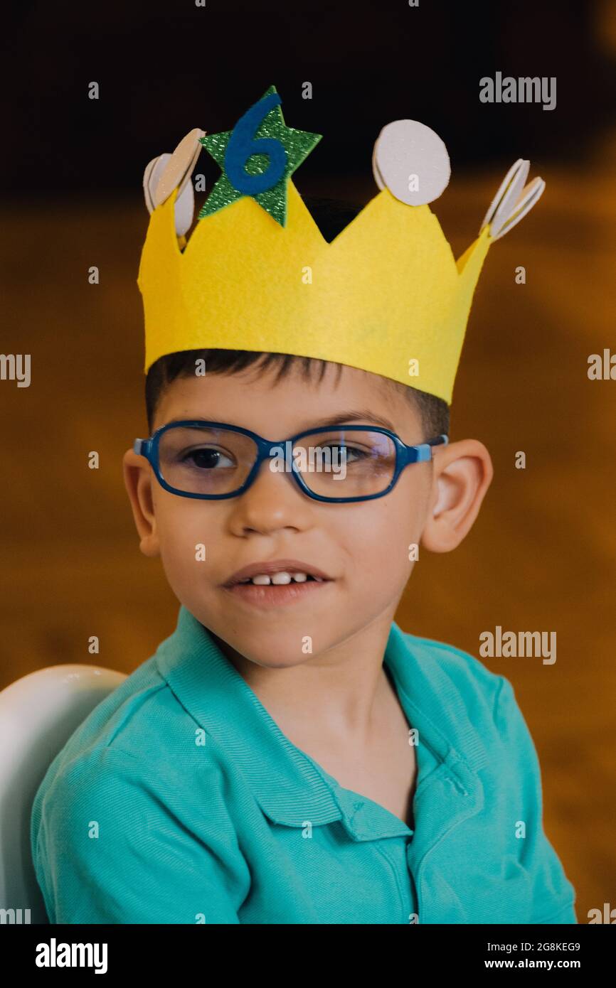 retrato chico caucásico con gafas sentado sonriendo con una corona de