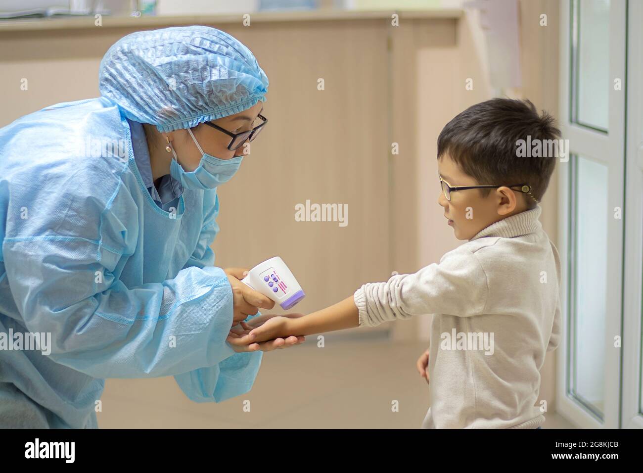 enfermera en traje médico desechable mide la temperatura corporal de los  niños que usan gafas con termómetro médico infrarrojo. Pistola de termómetro  Isométrica M Fotografía de stock - Alamy