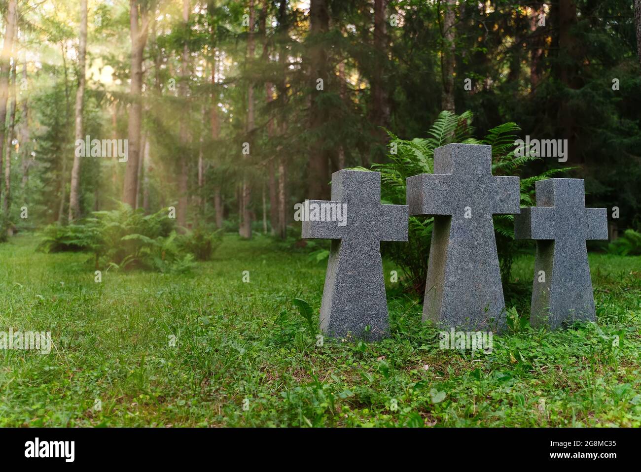 Tres cruces de piedra en un cementerio en el bosque. Foto de stock