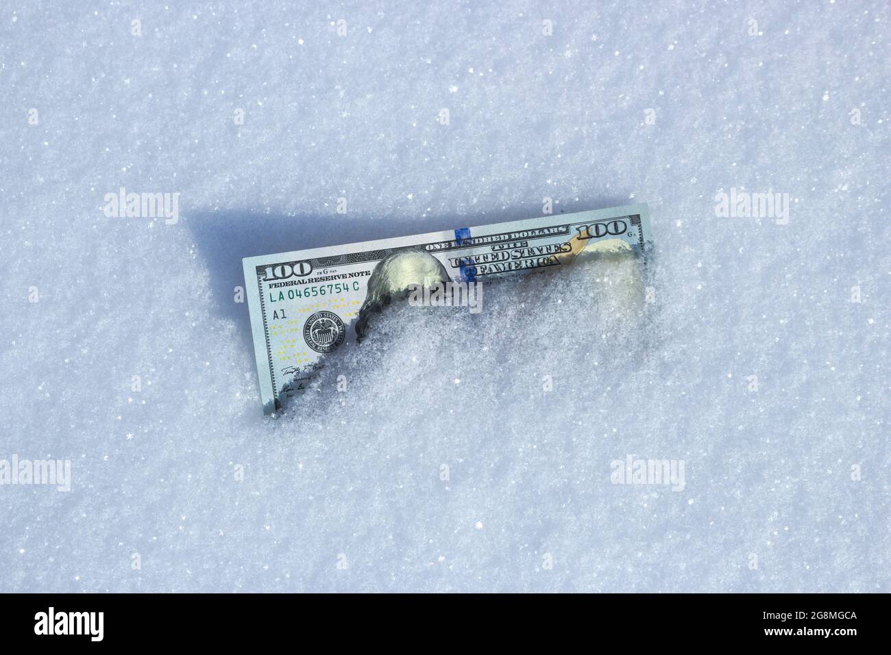 La moneda estadounidense se encuentra en la nieve. Concepto de dinero congelado. Foto de stock