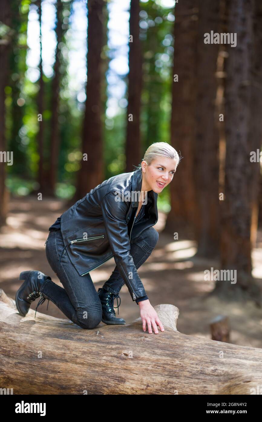 Mujer joven en un gran tronco caído de secoya en el bosque de secoya Foto de stock