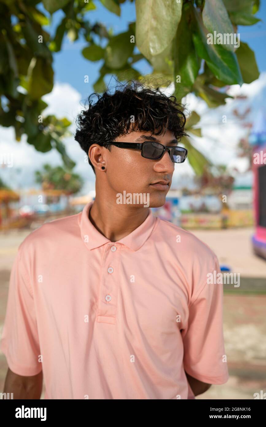 retrato de un joven hispano gay mirando hacia el lado, con una camisa de polo rosa Foto de stock