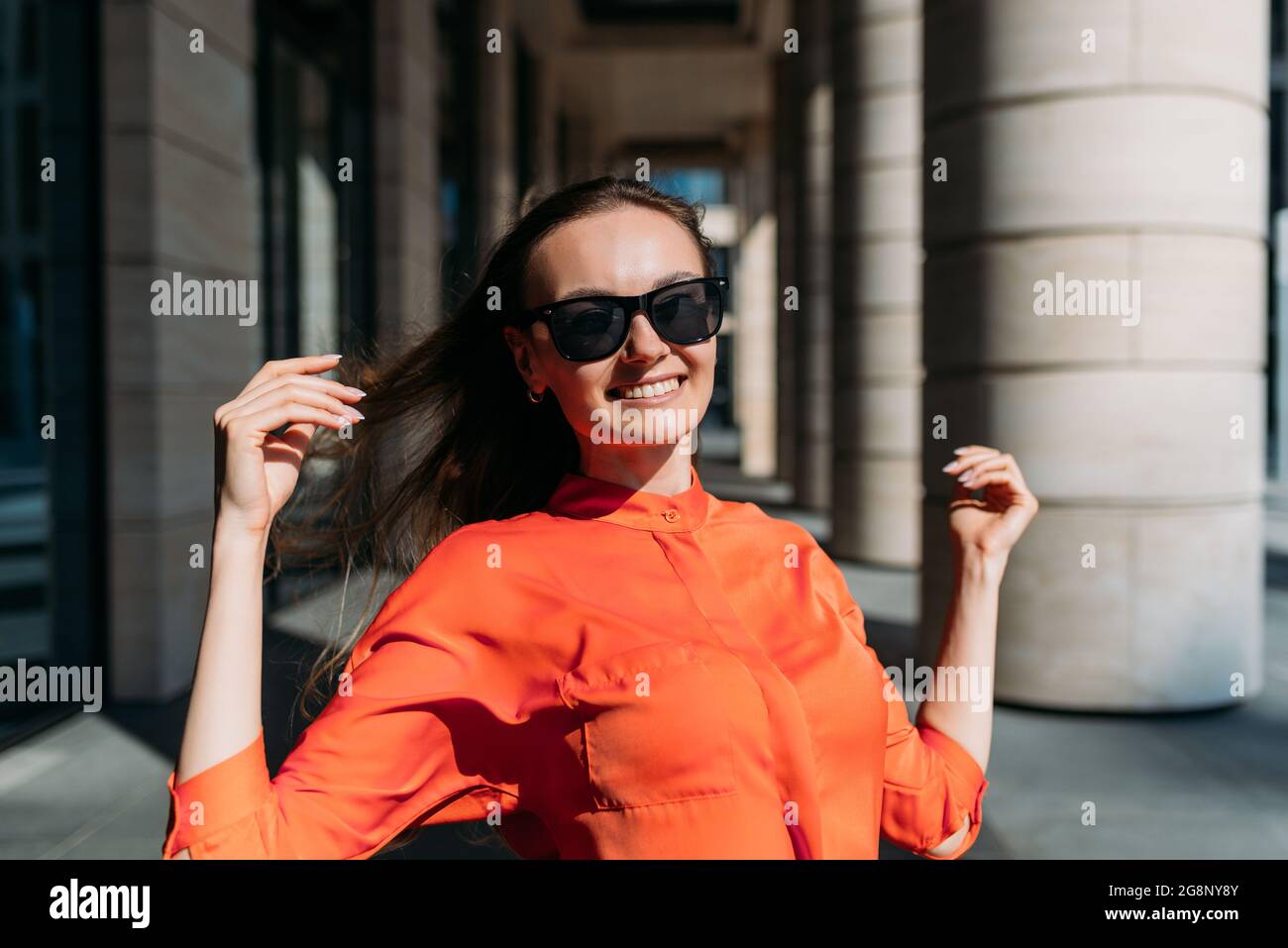 Chica caucásica en gafas de sol y ropa informal sonriendo en una caminata Foto de stock
