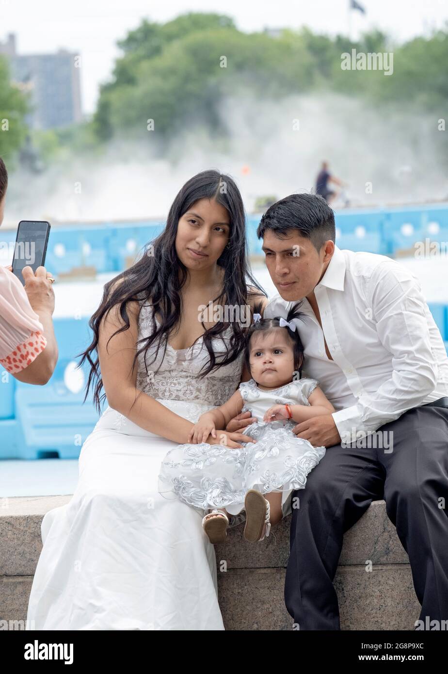 Una familia sudamericana pose para una foto de teléfono celular cerca del Unisphere en Flushing Meadows Corona Park en Queens, Nueva York. Foto de stock