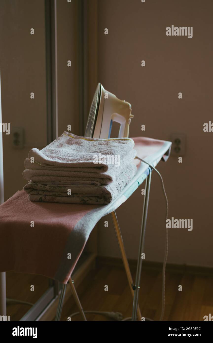 Una plancha y una pila de ropa de cama planchada en la tabla de planchar  Fotografía de stock - Alamy