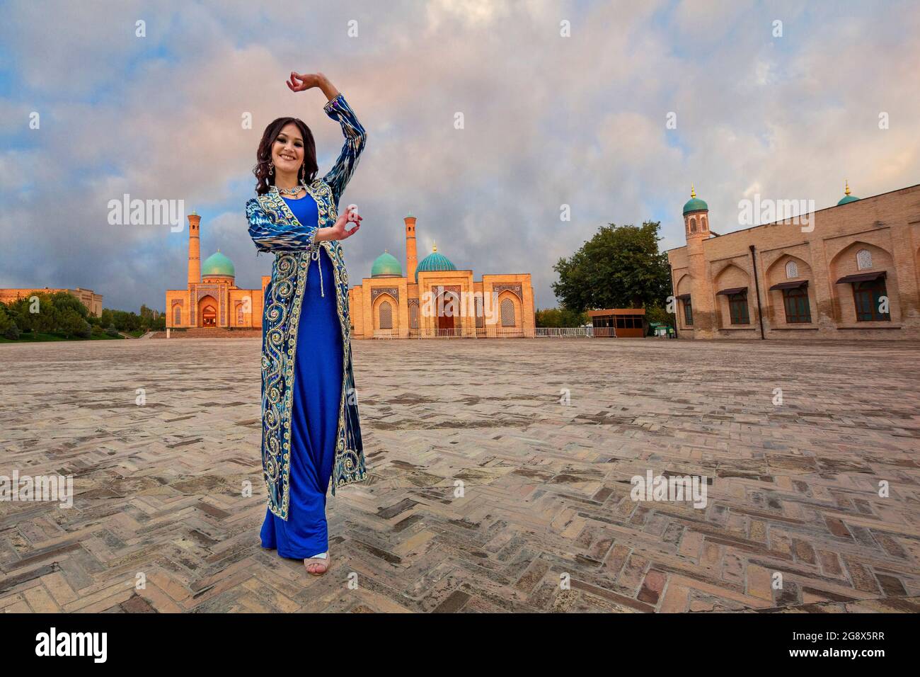 Mujer uzbeka vestida con la mezquita Khast Imam al fondo en Tashkent, Uzbekistán Foto de stock
