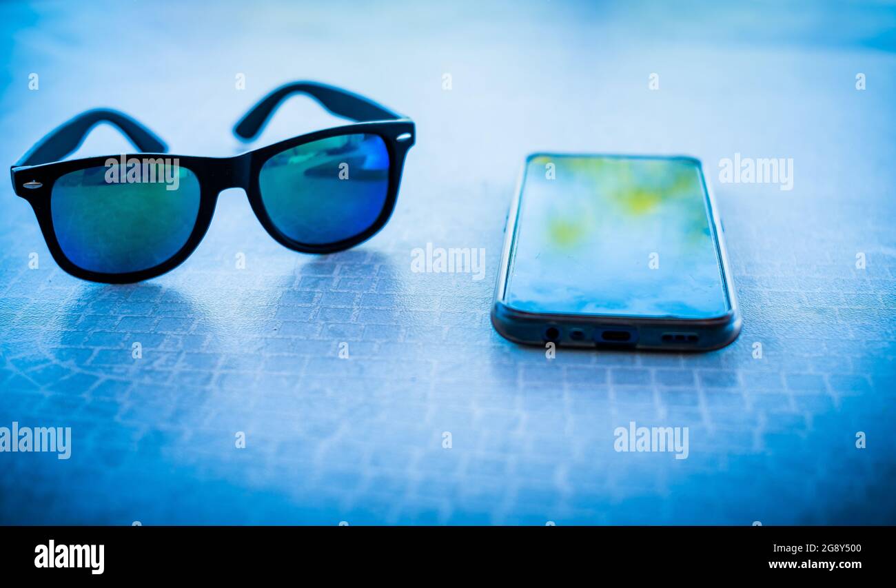 teléfono inteligente y gafas de sol con lentes de colores en una mesa de  terraza Fotografía de stock - Alamy