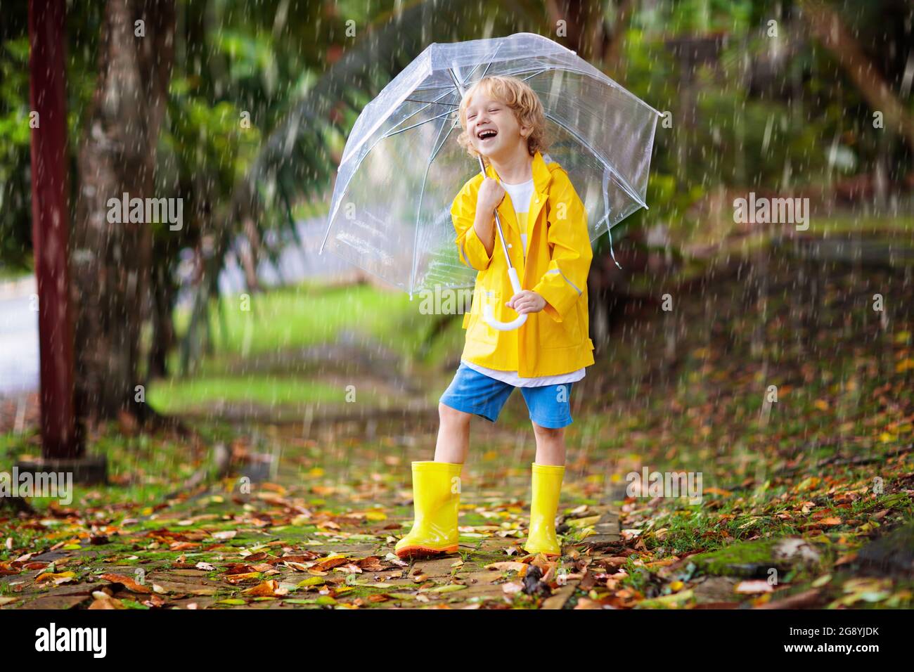 Niño Jugando Bajo La Lluvia De Otoño. Niño Con Paraguas. Niño Corriendo En  Un Parque En Temporada De Otoño. Diversión Al Aire Libre Para Niños En  Cualquier Clima. Ropa Impermeable Para La