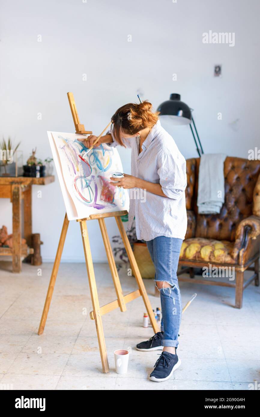 Joven artista pintando sobre lienzo en estudio de arte Foto de stock