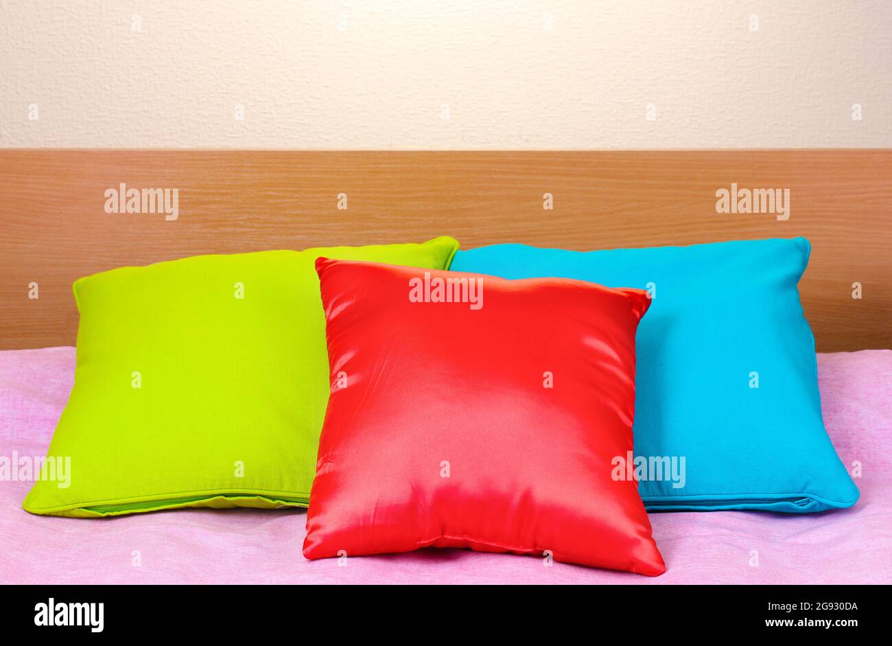 almohadas luminosas en la cama sobre fondo beige Fotografía de stock - Alamy